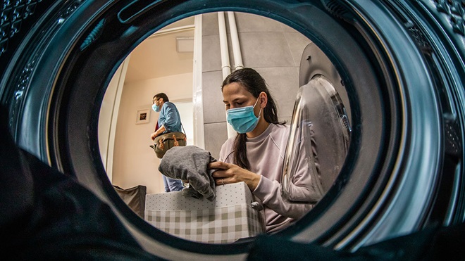 woman doing laundry wearing a face mask
